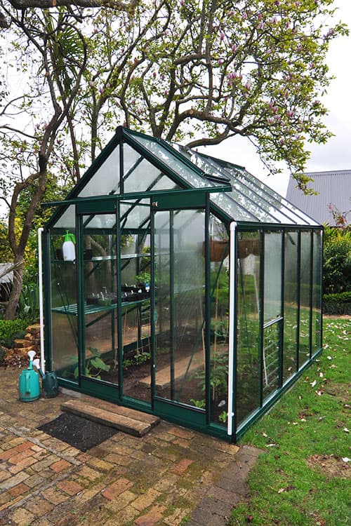 A Trulux Harvest glasshouse in a mature garden